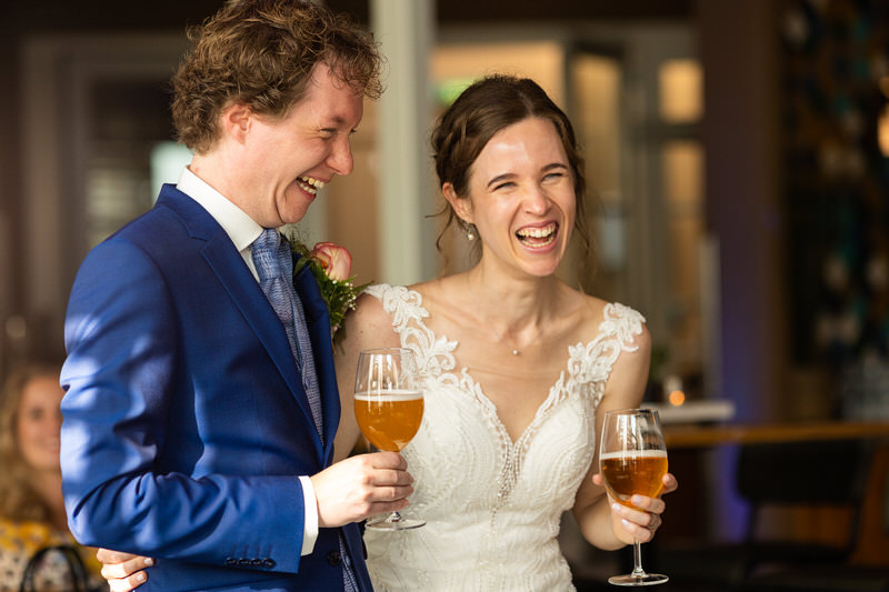 Een trouwfotograaf kiezen, hoe doe je dat - lachend bruidspaar met bier in hun handen