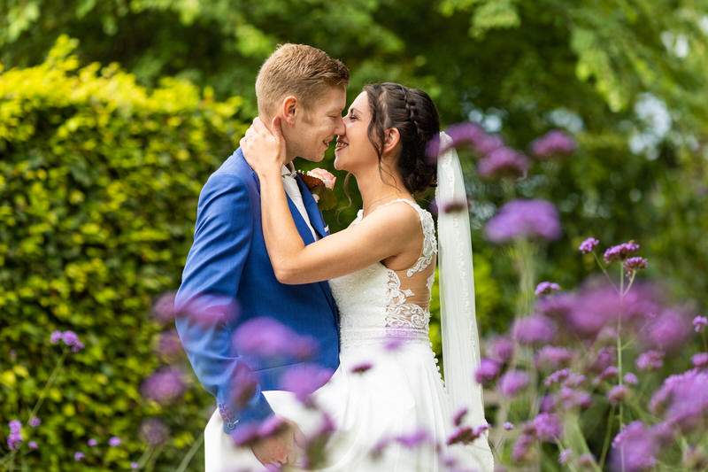 Wat kost een trouwfotograaf? - bruidspaar in tuin met bloemen